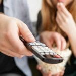 man holding remote woman eating popcorn